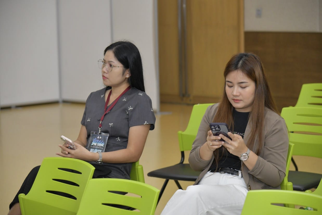 กระดูกสันหลัง ผู้หญิงสองคนนั่งในการประชุม BASIC SPINE COURSE 2025 โดยใช้โทรศัพท์มือถือ ออร์โธปิดิกส์